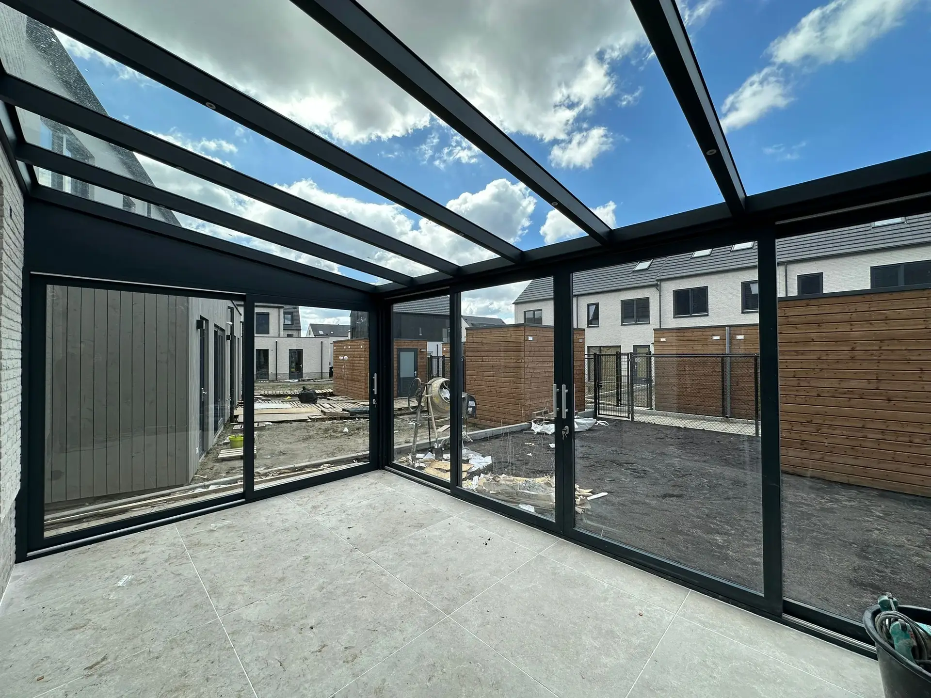 Moderne Überdachung mit Glaswänden in einem Neubau-Gartenprojekt