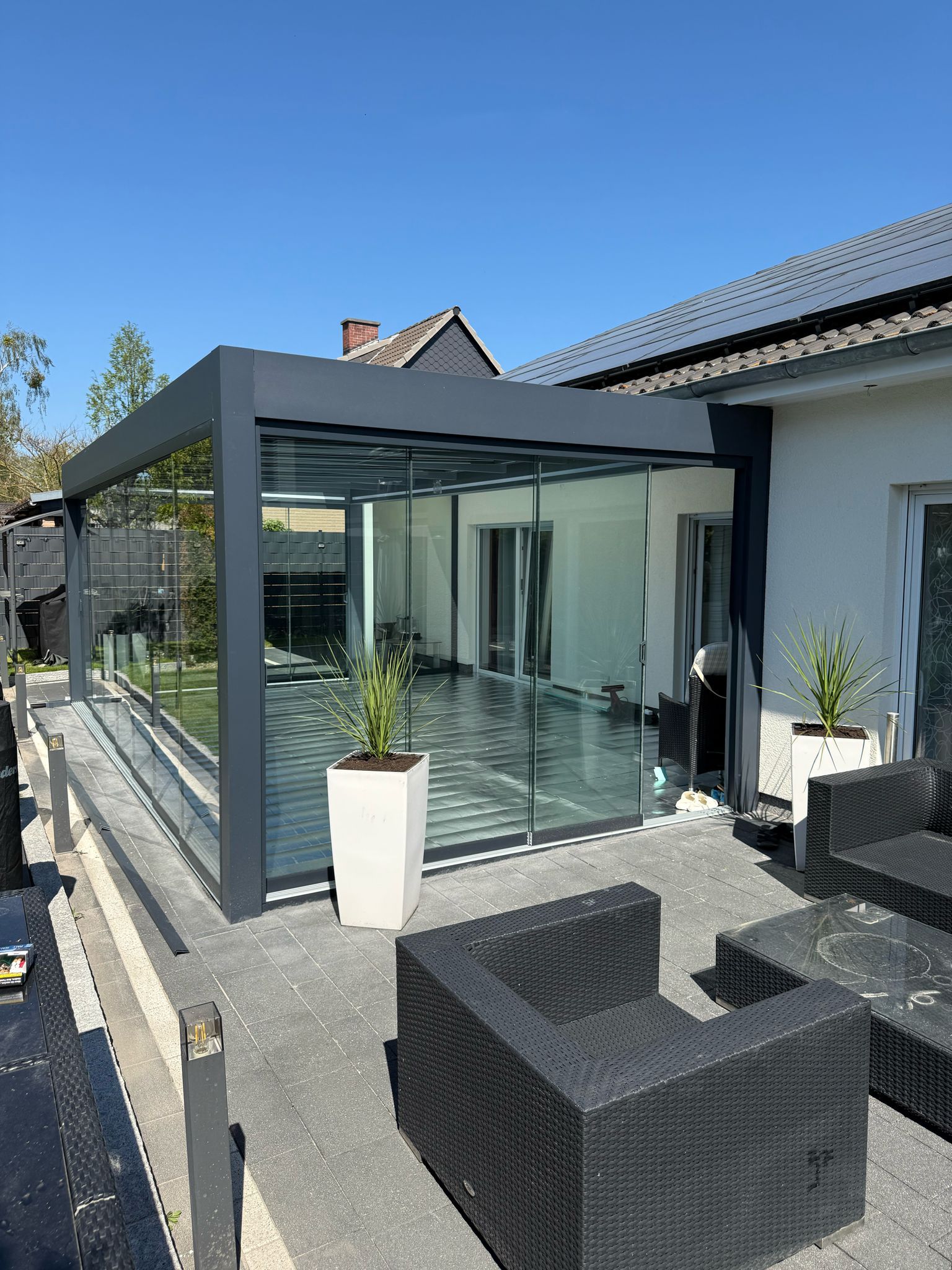 Moderne Cube Terrassenüberdachung mit Flachdach und Glasschiebewänden auf der Terrasse