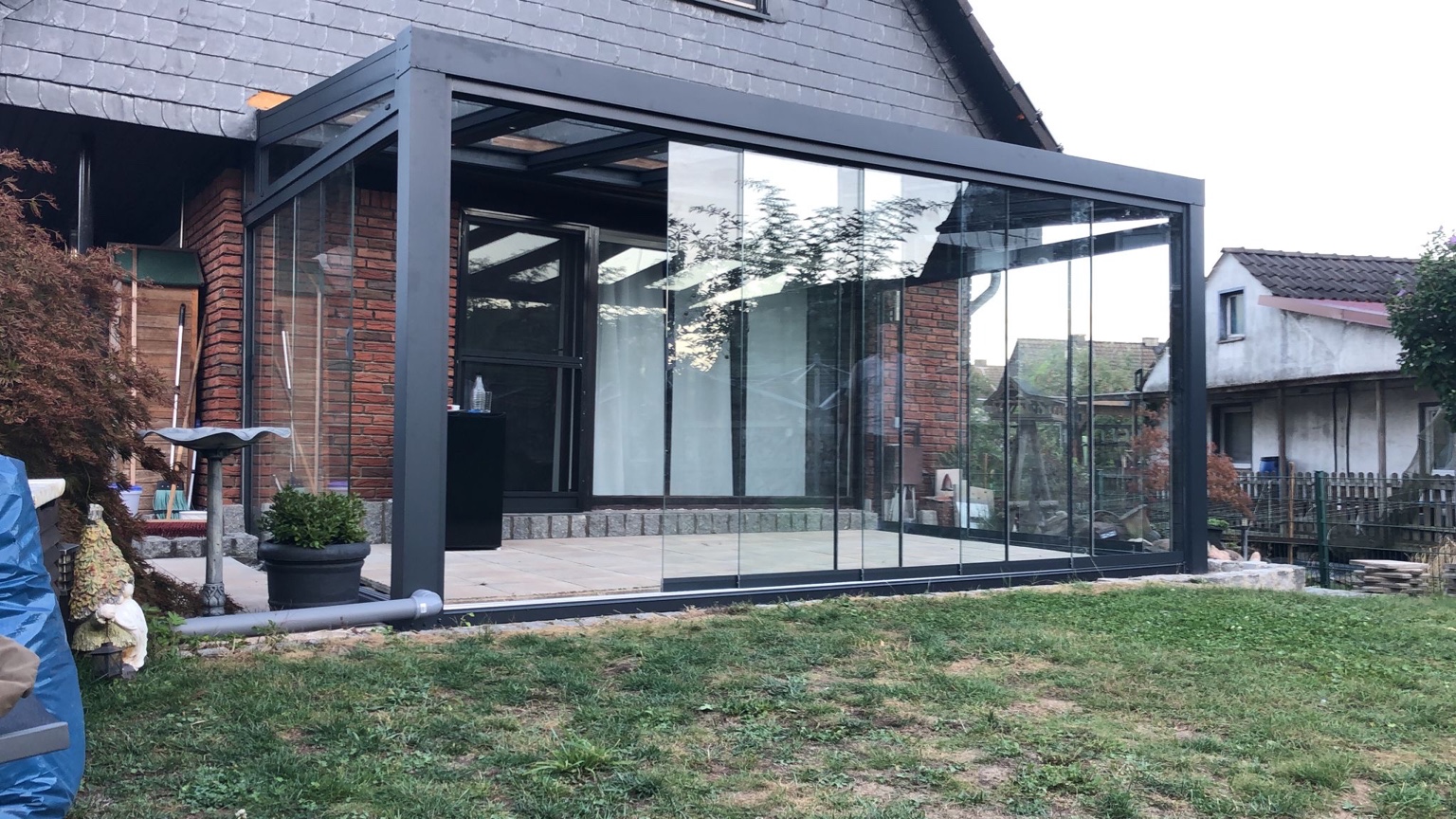 Moderne Terrassenüberdachung aus Aluminium mit Glasdach und Glasschiebewänden in Anthrazit
