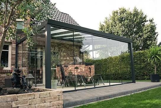 Terrassenüberdachung aus Aluminium mit Glasdach und Glasschiebewänden im Garten