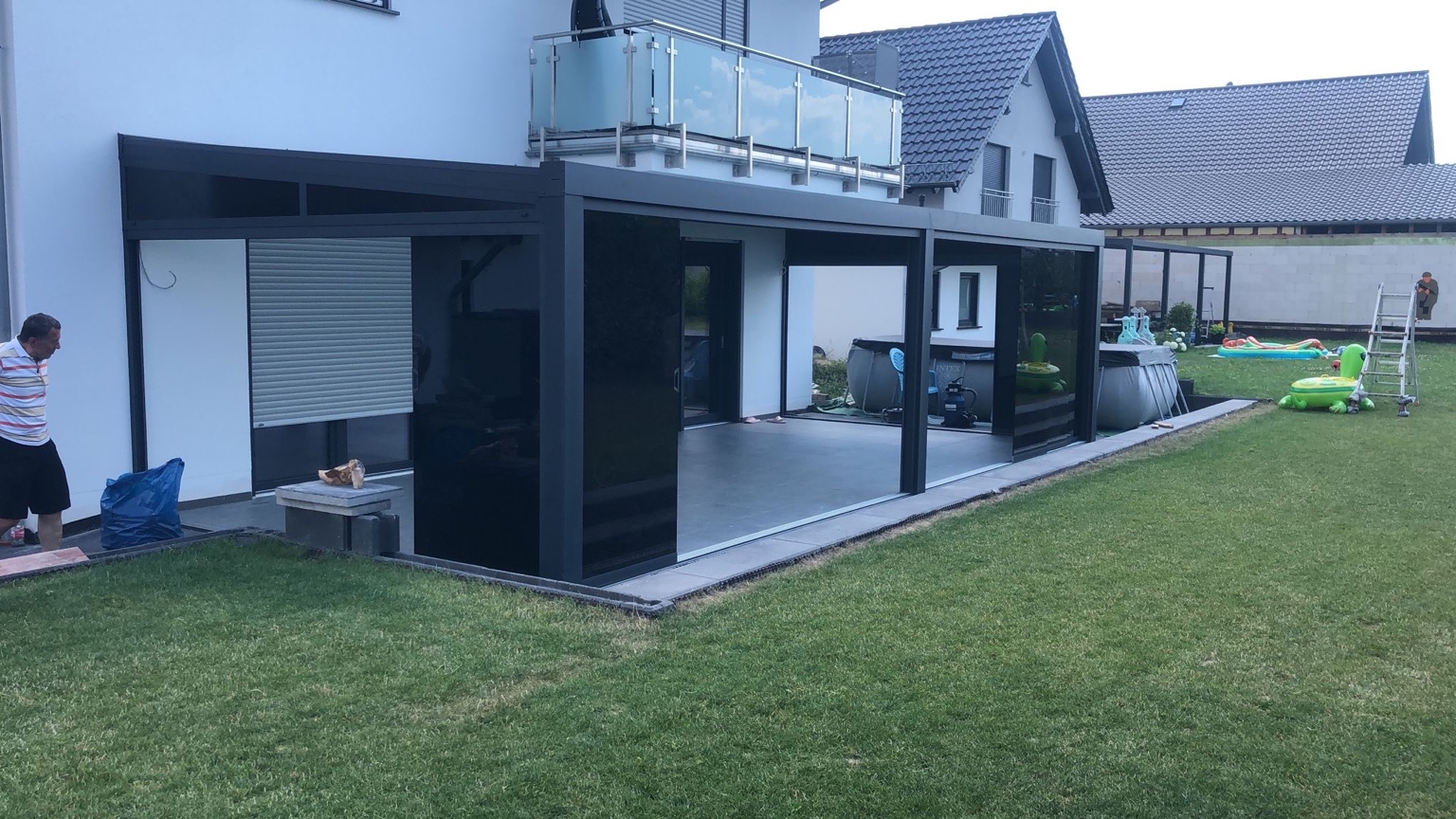 Terrassenüberdachung aus Aluminium mit Glasdach und Seitenwänden über einer modernen Terrasse