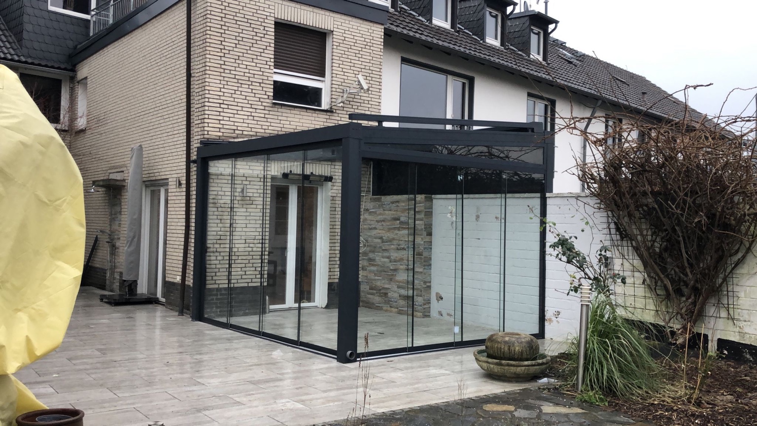 Moderne Terrassenüberdachung aus Aluminium mit großen Glasschiebewänden als Terrassenanbau