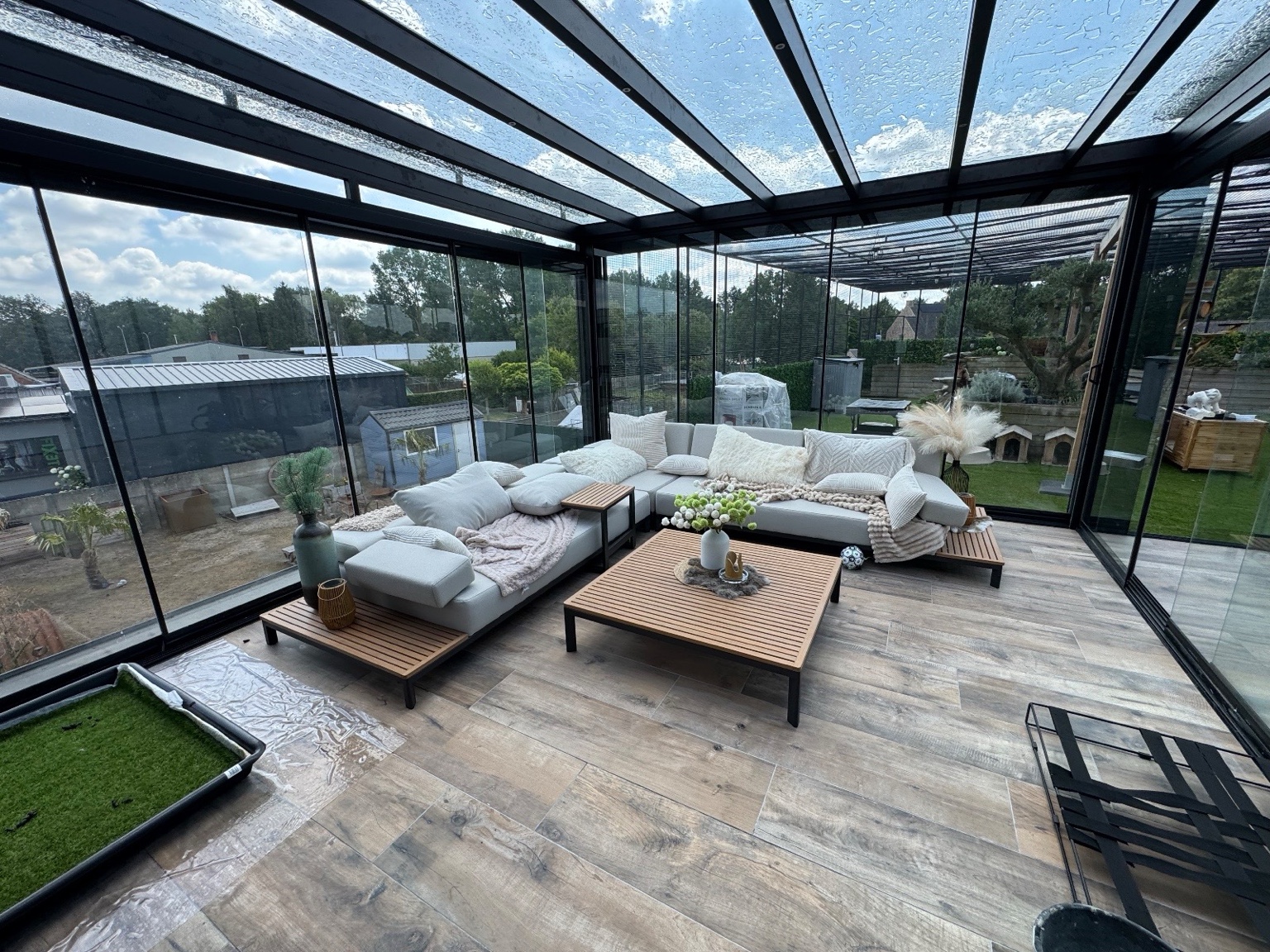 Terrassenüberdachung aus Aluminium mit Glasdach und Glasschiebewänden über einer modernen Terrasse